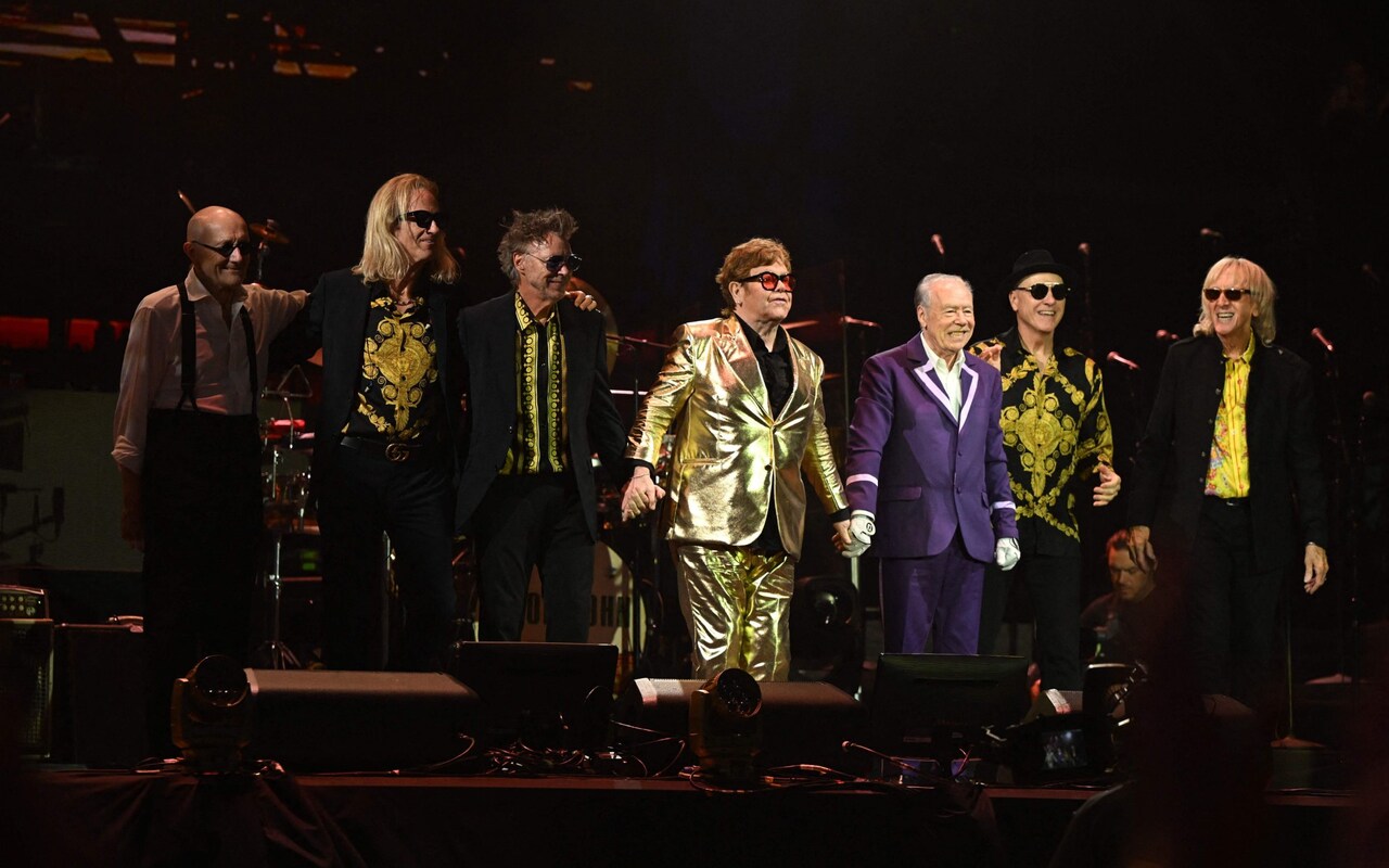 Elton John in a gold Tom Cridland suit with his band